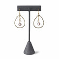 Golden Teardrop Crystal Earrings — a champagne stone and clear crystals in a hammered gold teardrop, on a dark earring stand