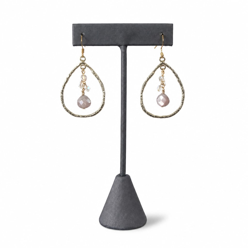 Golden Teardrop Crystal Earrings — a champagne stone and clear crystals in a hammered gold teardrop, on a dark earring stand
