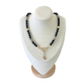 The Jennie Necklace on a display bust: black beads with faceted hematite and gold accents, closing on a gold oval clasp with two small drops