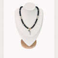 The Jonna Necklace on a display bust: black beads with clear crystals, gold rondelles and a silver revolver charm