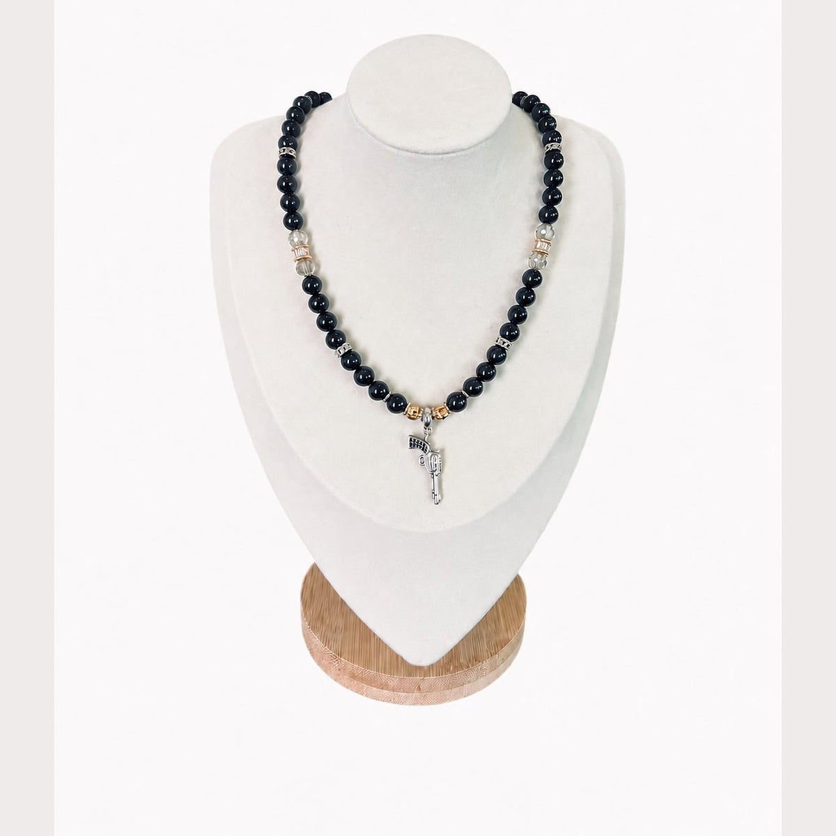 The Jonna Necklace on a display bust: black beads with clear crystals, gold rondelles and a silver revolver charm