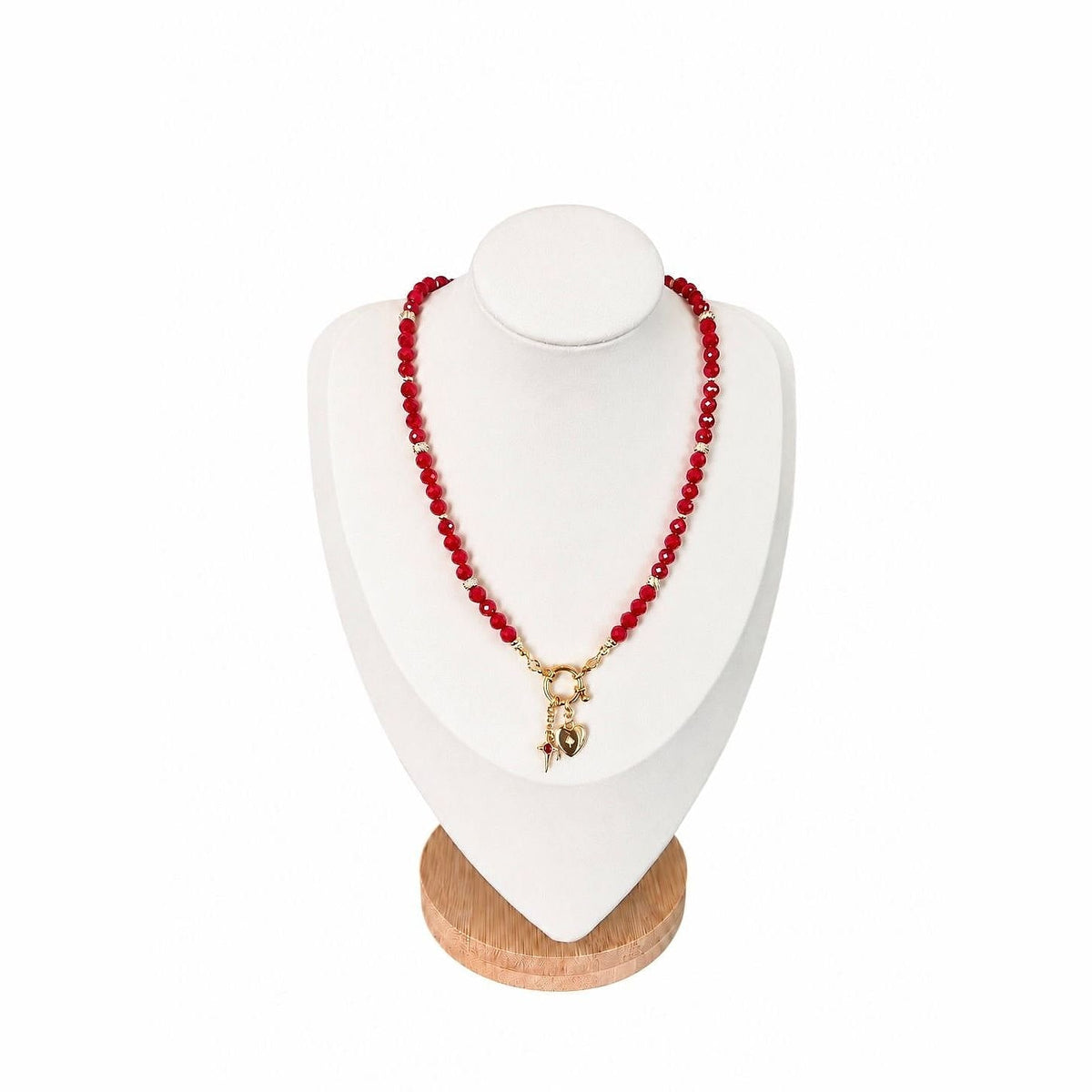 The Julia Necklace on a display bust: faceted ruby-red beads with a gold ring clasp, heart and star charms