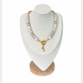 The Krissa Necklace on a display bust: white banded agate and grey pearls with gold pavé rondelles, a gold ring clasp and a crystal clover charm