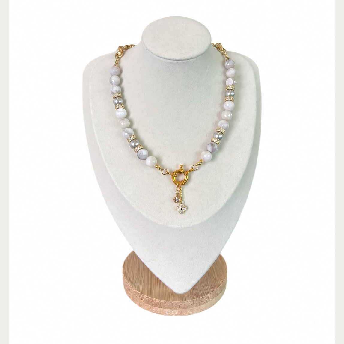 The Krissa Necklace on a display bust: white banded agate and grey pearls with gold pavé rondelles, a gold ring clasp and a crystal clover charm