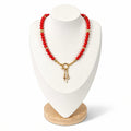 The Larina Necklace on a display bust: vibrant red coral beads with a gold clasp and star charm