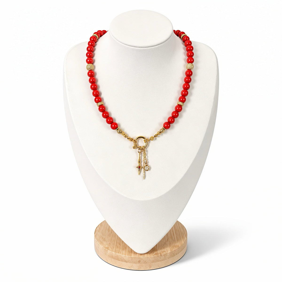 The Larina Necklace on a display bust: vibrant red coral beads with a gold clasp and star charm